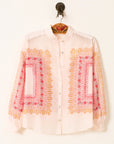 White shirt with pink and yellow embroidery on a hanger against a white background