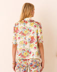Person wearing a colorful floral outfit on a beige background