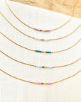 Set of gold necklaces with colorful beads on a white fabric background