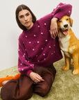 Person wearing a purple sweater with white polka dots, sitting on the floor next to a dog. Elia Mulberry Balloon Sweater from Alemais