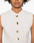 White sleeveless top with gold buttons worn by a person on a white background