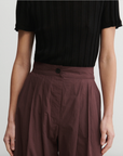 Person wearing a black top and brown pants on a plain background