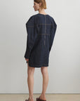 Woman wearing a dark denim dress against a plain background