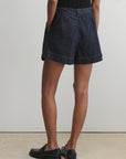 Person wearing dark denim shorts on a plain background