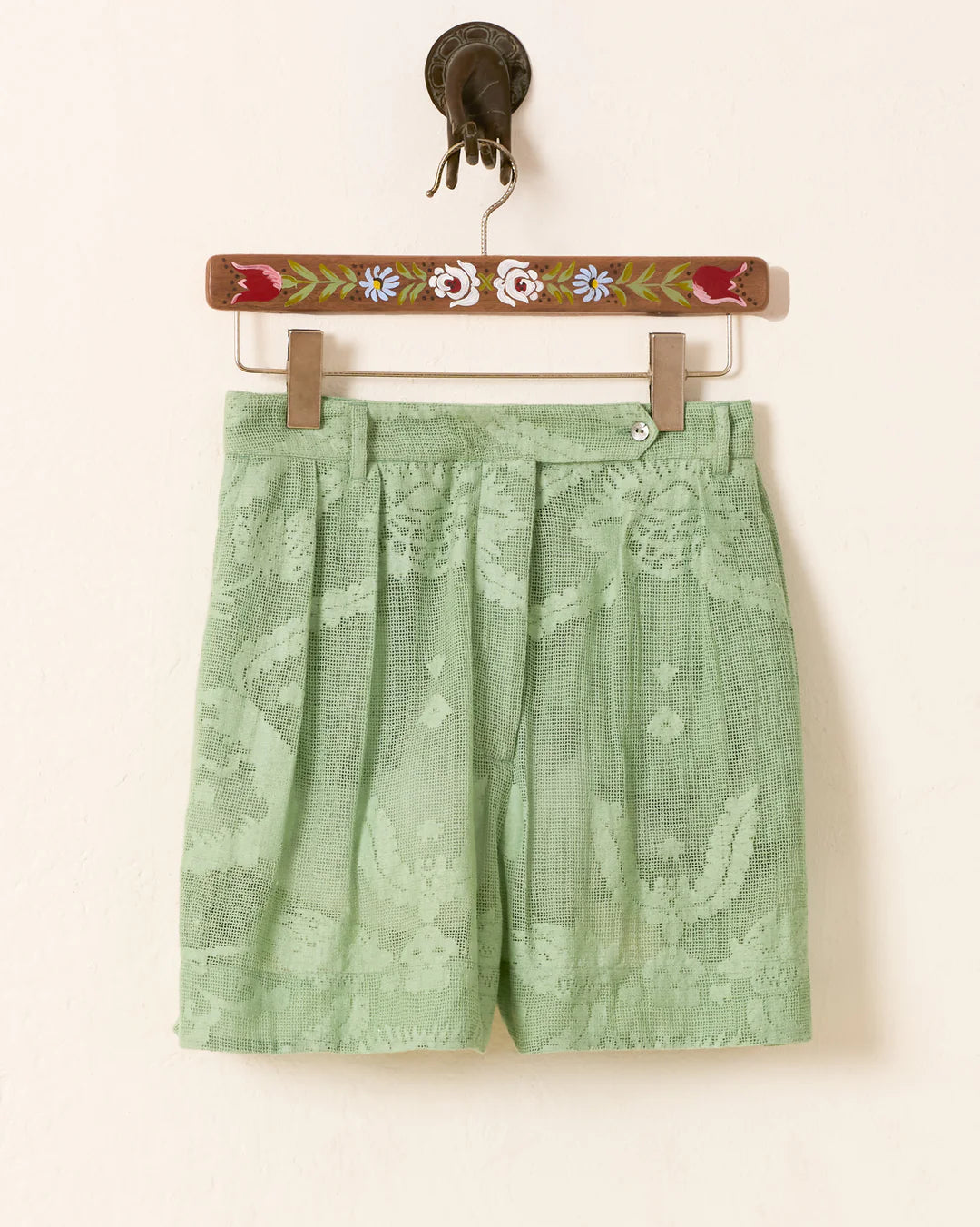 Deena Eucalyptus shorts with floral pattern on a hanger against a white background