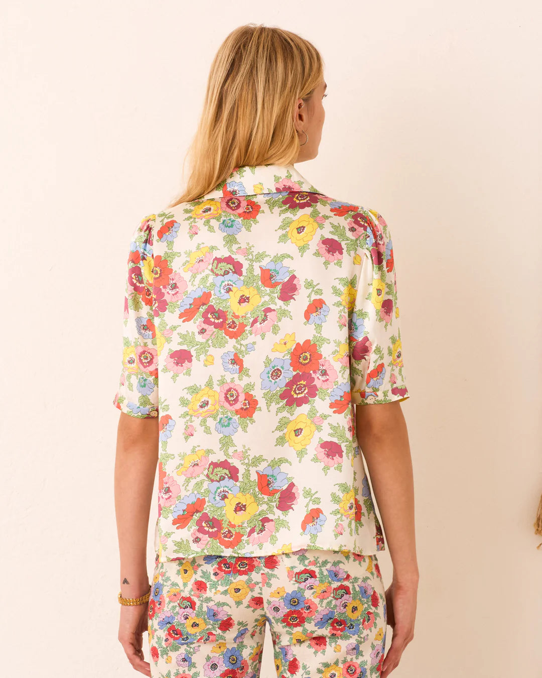 Person wearing a colorful floral outfit on a beige background