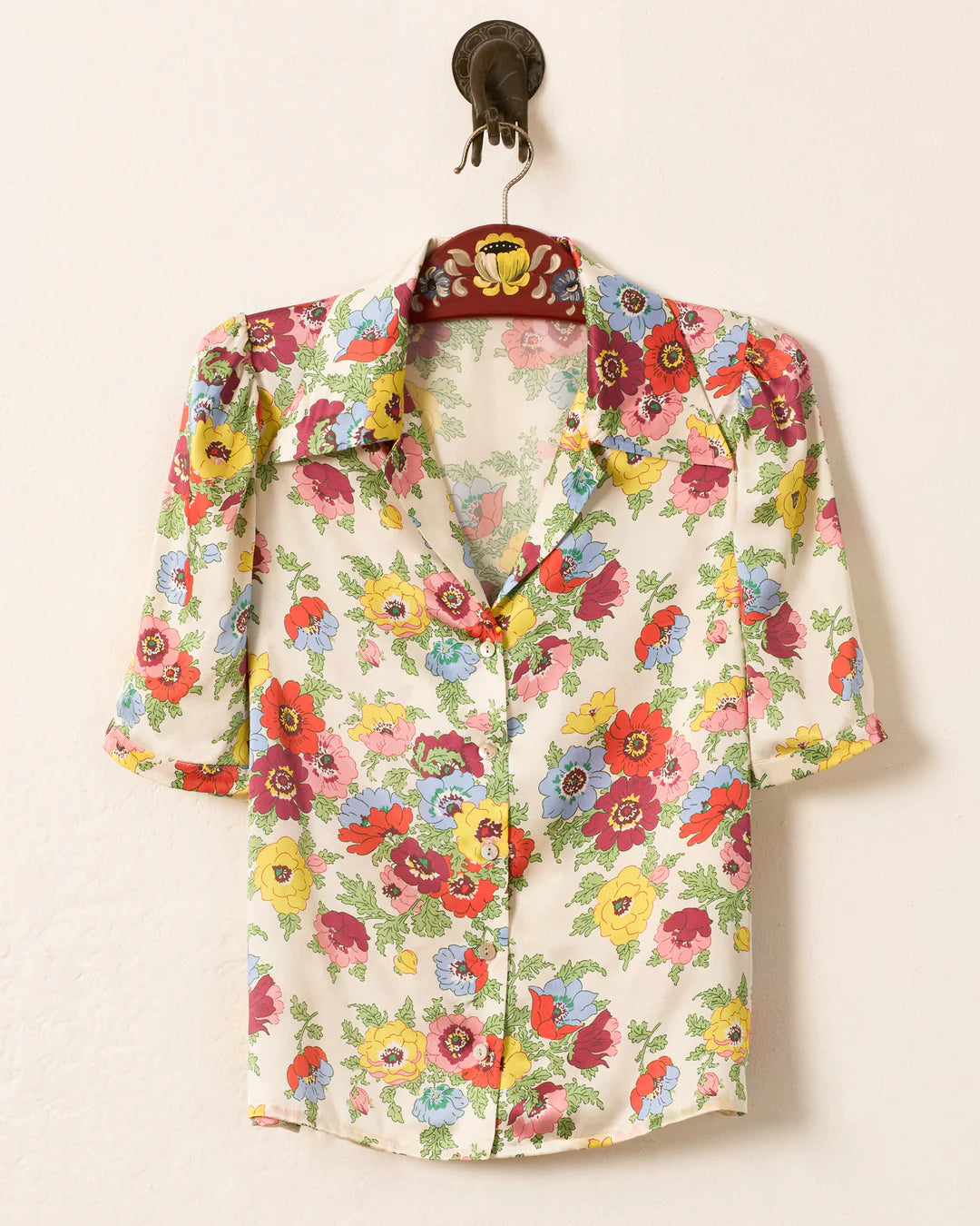 Floral patterned shirt on a hanger against a white background