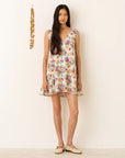 Woman wearing a colorful floral dress against a plain background