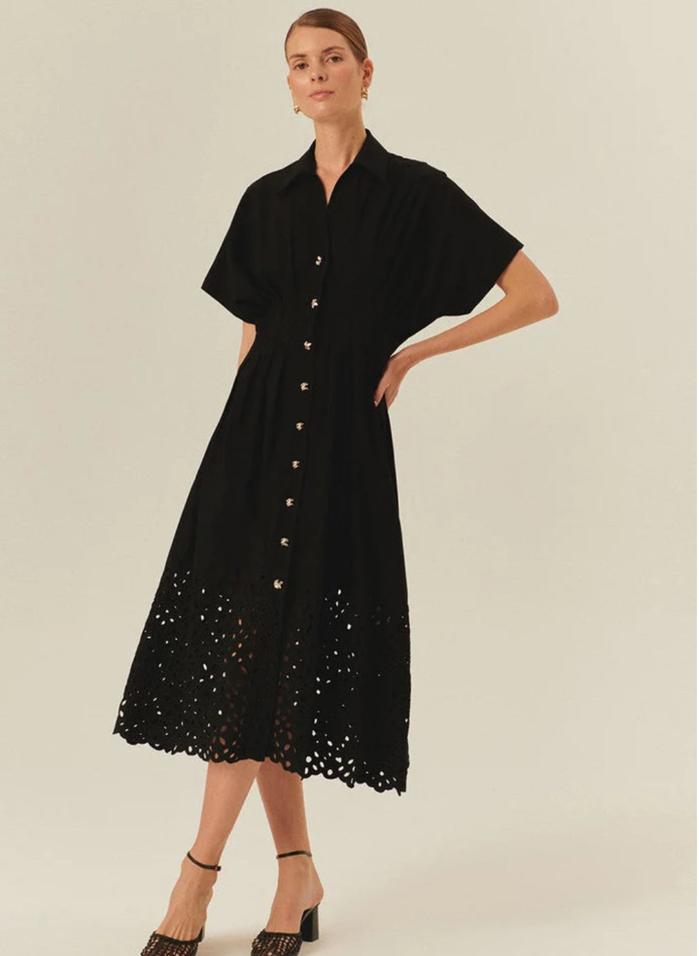 Woman wearing a black dress with lace details on a plain background. Exquise Vera Dress.