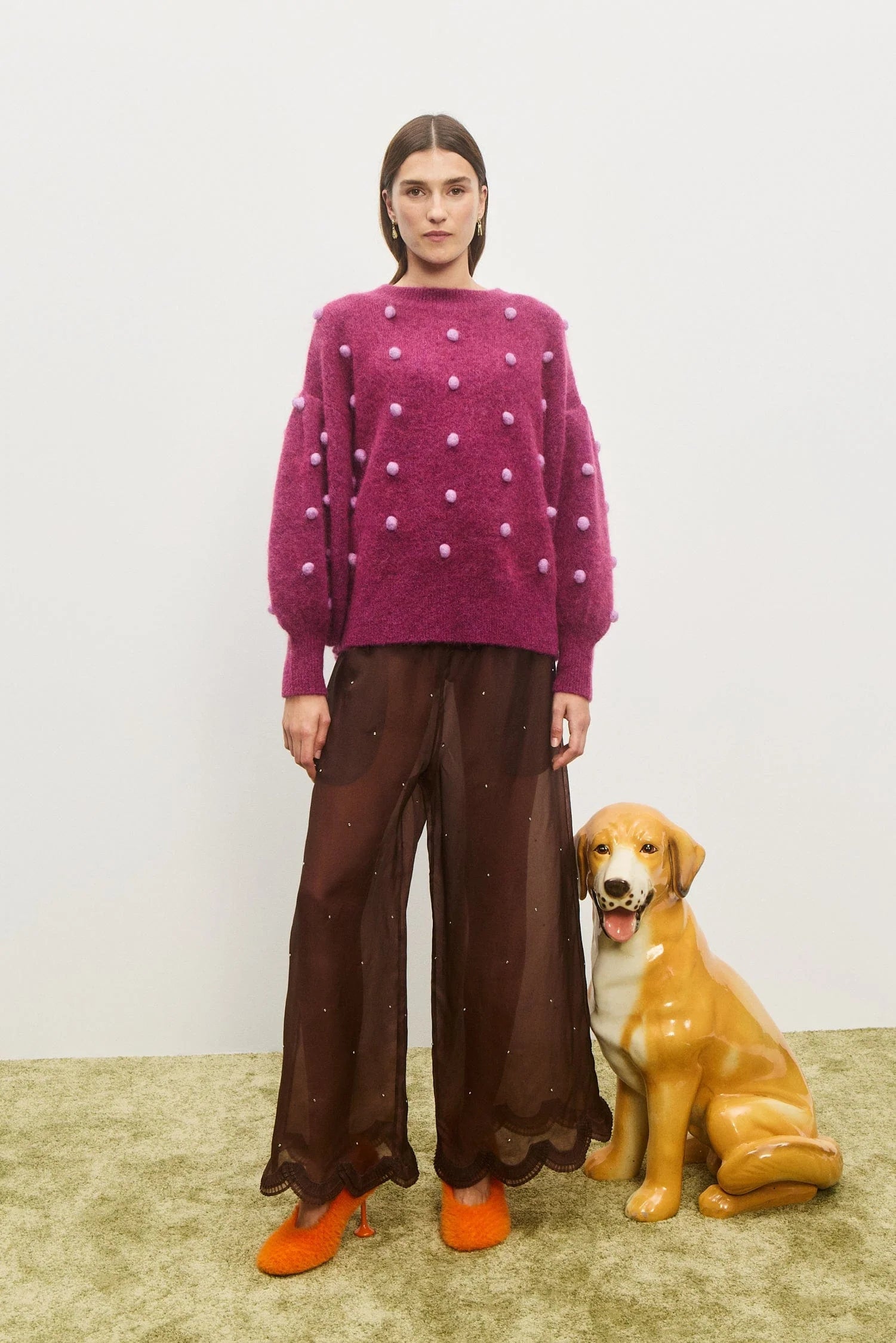 Person wearing a purple sweater with white polka dots and brown pants, standing next to a dog on a light-colored floor. Elia Mulberry Balloon Sweater