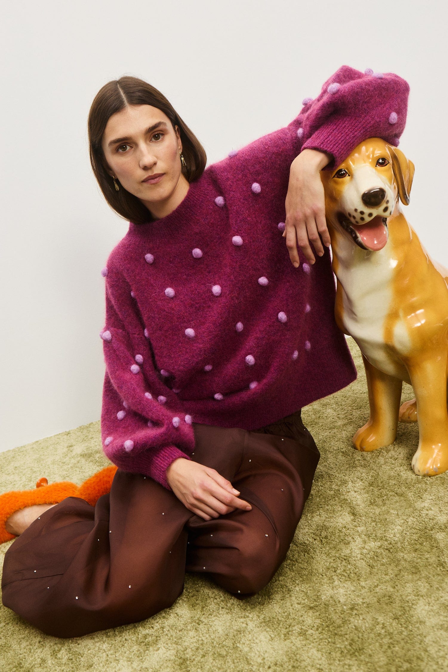 Person wearing a purple sweater with white polka dots, sitting on the floor next to a dog. Elia Mulberry Balloon Sweater from Alemais