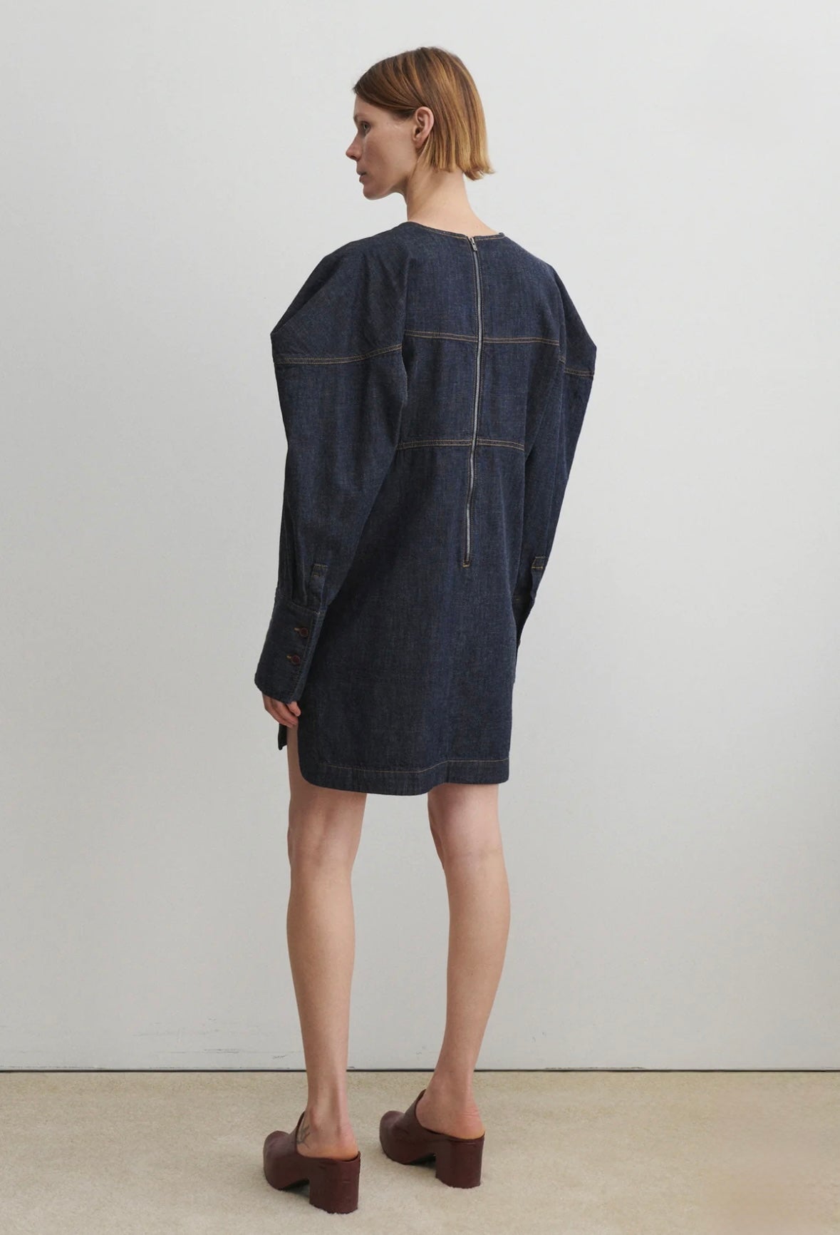Woman wearing a dark denim dress against a plain background